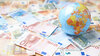 Weltkugel vor Geldscheinen_ Welt ohne Bargeld